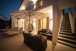 a house with a patio with a couch and an umbrella at Villa Sunset in Kastel Novi