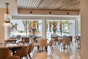 un restaurante con mesas, sillas y ventanas grandes en Herbert Samuel Milos Dead Sea en Ein Bokek