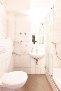 a white bathroom with a toilet and a sink at BrauHotel Bonn in Bonn