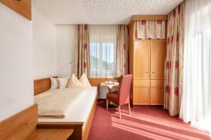 a hotel room with a bed and a chair and a window at Hotel Alpenhof in Bad Hofgastein