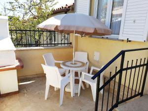 a table with chairs and an umbrella on a balcony at Apartman Vida in Pula