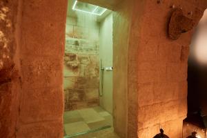 a bathroom with a walk in shower next to a stone wall at Musae Relais & SPA in Polignano a Mare