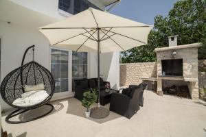 a patio with a swing and an umbrella and a fireplace at Villa Sunset in Kastel Novi