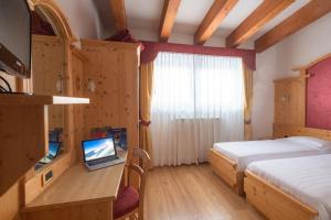 Schlafzimmer mit einem Bett und einem Laptop auf einem Schreibtisch in der Unterkunft Hotel Angelo in Passo del Tonale
