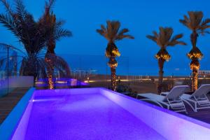 
a beach scene with a pool and chairs at Milos Hotel Dead Sea in Ein Bokek
