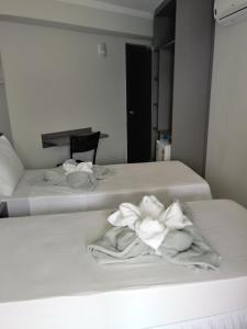 Dos camas en una habitación con toallas blancas. en Hotel Bellagio en Campo Grande