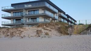 a building sitting on top of a sandy beach at Apartament Fala Gardenia Seaside in Dziwnów