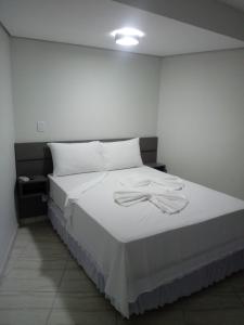 a bedroom with a bed with white sheets at Hotel Bellagio in Campo Grande