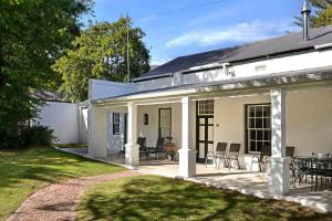 a white house with chairs and a patio at Bo La Motte Farm Cottages in Franschhoek
