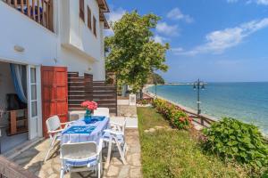 a table and chairs on a patio next to the ocean at Agios Ioannis luxurious beachfront studio in Agios Ioannis Pelio