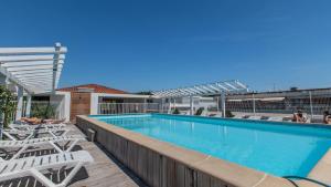 una piscina con sedie a sdraio bianche accanto ad essa di Vacancéole - Résidence Le Crystal a Cagnes-sur-Mer
