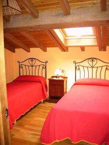 2 camas en una habitación con sábanas rojas en Casa Rural Carrio, en Taranes