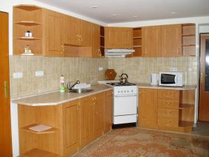 a kitchen with wooden cabinets and a white stove top oven at Guest House Boba in Štrba