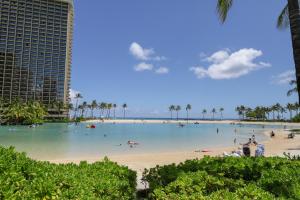 einen Strand mit Menschen im Wasser und Palmen in der Unterkunft Harbor View Plaza #1203 in Honolulu