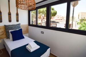 a bedroom with a bed with blue and white sheets and windows at Letmalaga Carlos Haya in Málaga +126 photos