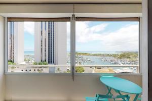 d'une fenêtre avec une chaise bleue et une vue sur le port. dans l'établissement Harbor View Plaza #1203, à Honolulu