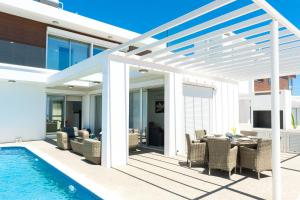 une pergola blanche au-dessus d'une terrasse avec piscine dans l'établissement Villa Rubi, à Ayia Napa