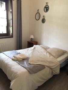 ein Bett mit weißer Bettwäsche und Kissen in einem Schlafzimmer in der Unterkunft GITE DES CHOUETTES in Muron
