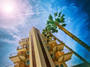 アルバ・アドリアティカにあるAlmaluna Hotel & Resortのヤシの木が2本並ぶ高層ビル
