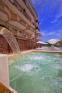 a pool with a water fountain in front of a building at Almaluna Hotel & Resort in Alba Adriatica