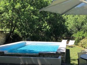 una piscina con sombrilla, mesa y sillas en Le Pont de L'orme, en Malaucène