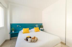 a white bed with a bowl of food on it at Résidence Thalacap in Cap d'Agde