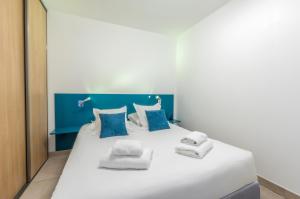 a large white bed with blue and white pillows at Résidence Thalacap in Cap d'Agde
