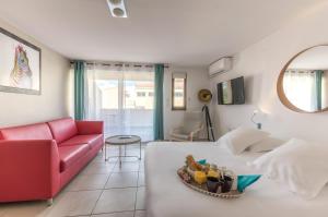 a living room with a bed and a red couch at Résidence Thalacap in Cap d'Agde