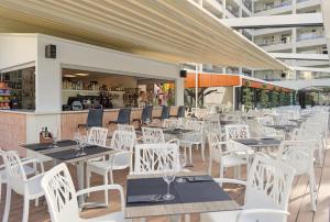ein leeres Restaurant mit weißen Tischen und Stühlen in der Unterkunft H10 Salou Princess in Salou