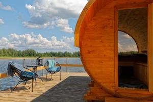 eine Hütte auf einem Dock mit einem Tisch und Stühlen in der Unterkunft Ezermala in Valdemārpils