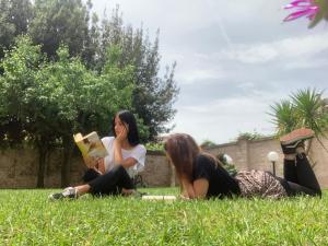 フォリーニョにあるOstello Palazzo Pierantoniの草の中に座って本を読む三人の少女