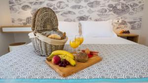 a tray of fruit and a basket with a glass of orange juice at Antony Suites (Adults Only) in Naxos Chora