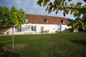 a large white house with a table and chairs in a yard at La Tuilerie du Paligny in Tallud-Sainte-Gemme