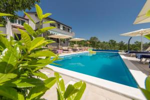 una piscina con sedie e ombrelloni accanto a un edificio di Villa Old Garden a Lovreć