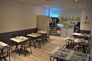 Logis - Le Neptune Hôtel & Restaurant في كايو سور مير: غرفة طعام مع طاولات وكراسي ومطبخ