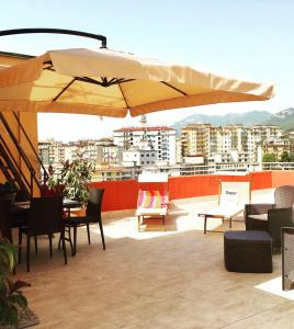 patio ze stołami i krzesłami oraz dużym parasolem w obiekcie Dimora Montpellier w mieście Salerno
