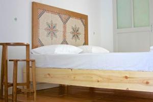 a bed with a wooden headboard and white sheets at Himara Hostel in Himare