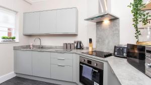 een keuken met witte kasten en een fornuis met oven bij Stylish and most central 2 bed City Centre Apartment in York