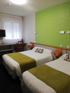 two beds in a room with a green wall at Hotel Restaurant La Grenouillère in Vitré