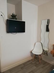 a living room with a tv and a white chair at Hotel Restaurant La Grenouillère in Vitré