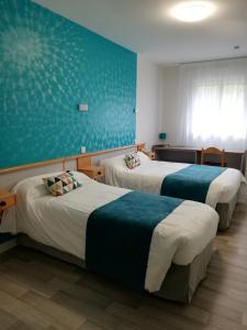 a hotel room with two beds and a blue wall at Hotel Restaurant La Grenouillère in Vitré