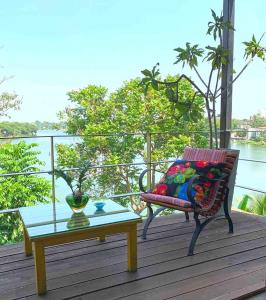 a bench and a table on a deck with a view of the water at Aathma Colombo House in Colombo