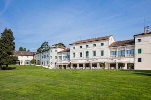 una fila di edifici bianchi con un prato verde di Villa Michelangelo Vicenza – Starhotels Collezione ad Arcugnano