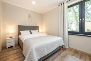 a bedroom with a bed and a large window at Apartamenty Parkowa 13 in Darłówko