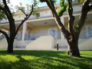 a building with stairs and trees in the grass at Residence VILLA FIORITA in Roccella Ionica