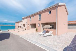 a pink building with two chairs and an umbrella at LUXURY APARTMENTS - LA VIR 1 & 2 in Vir