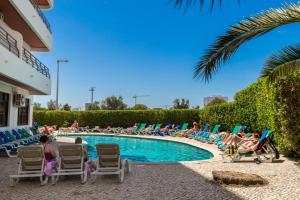 un grupo de personas sentadas en sillas alrededor de una piscina en Mirachoro Portimao, en Portimão