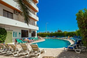 Una piscina con tumbonas y un hotel. en Mirachoro Portimao, en Portimão