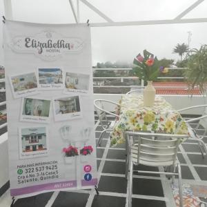 une table avec un vase de fleurs assis au-dessus d'une table dans l'établissement Elizabetha Hostal, à Salento