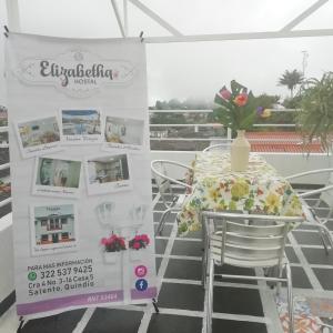 una mesa con un jarrón de flores sentada sobre una mesa en Elizabetha Hostal en Salento